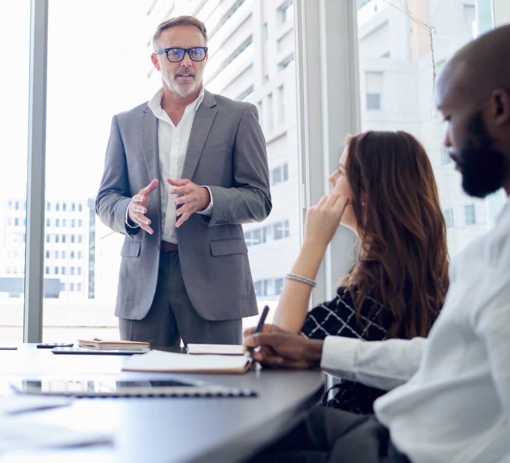 Businessman, mentor and meeting with team for presentation, corporate discussion or coaching at office. Man, CEO or executive talking to group of employees for business strategy or ideas at workplace.