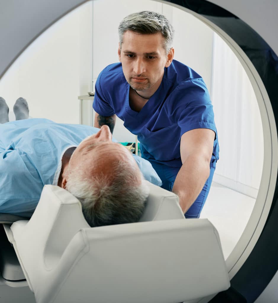 CT scan technologist overlooking patient