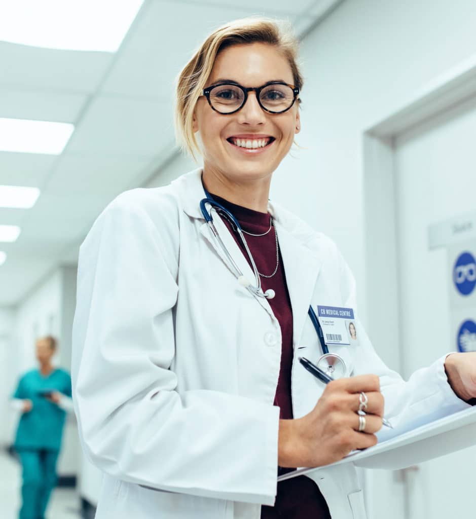 Female physician in hospital corridor writing prescription